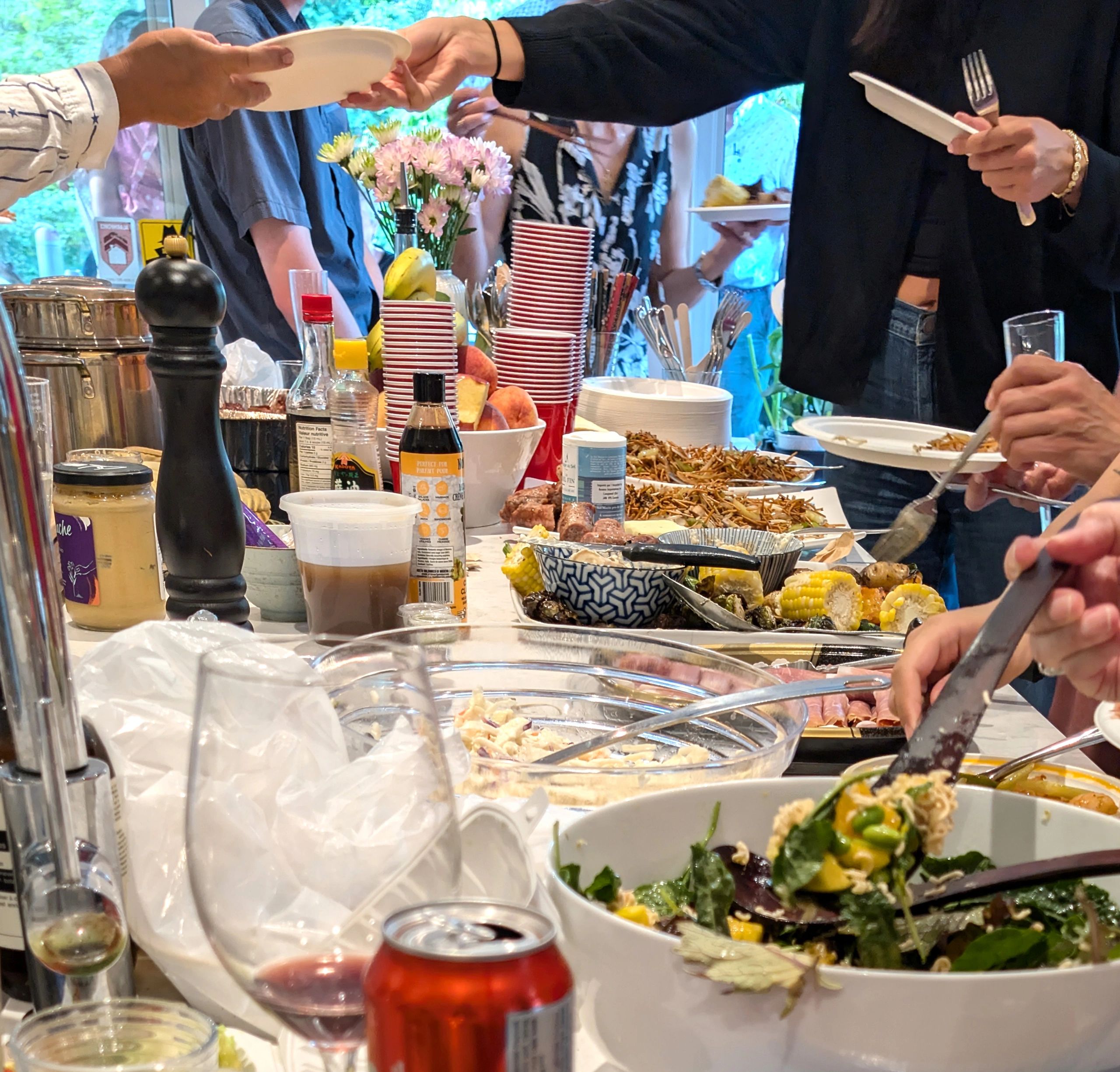 Guests serving themselves at a summer potluck table